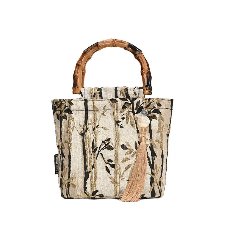 Beige polyester women's handbag with bamboo handles and pendant on neutral background
