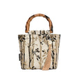Beige polyester women's handbag with bamboo handles and pendant on neutral background
