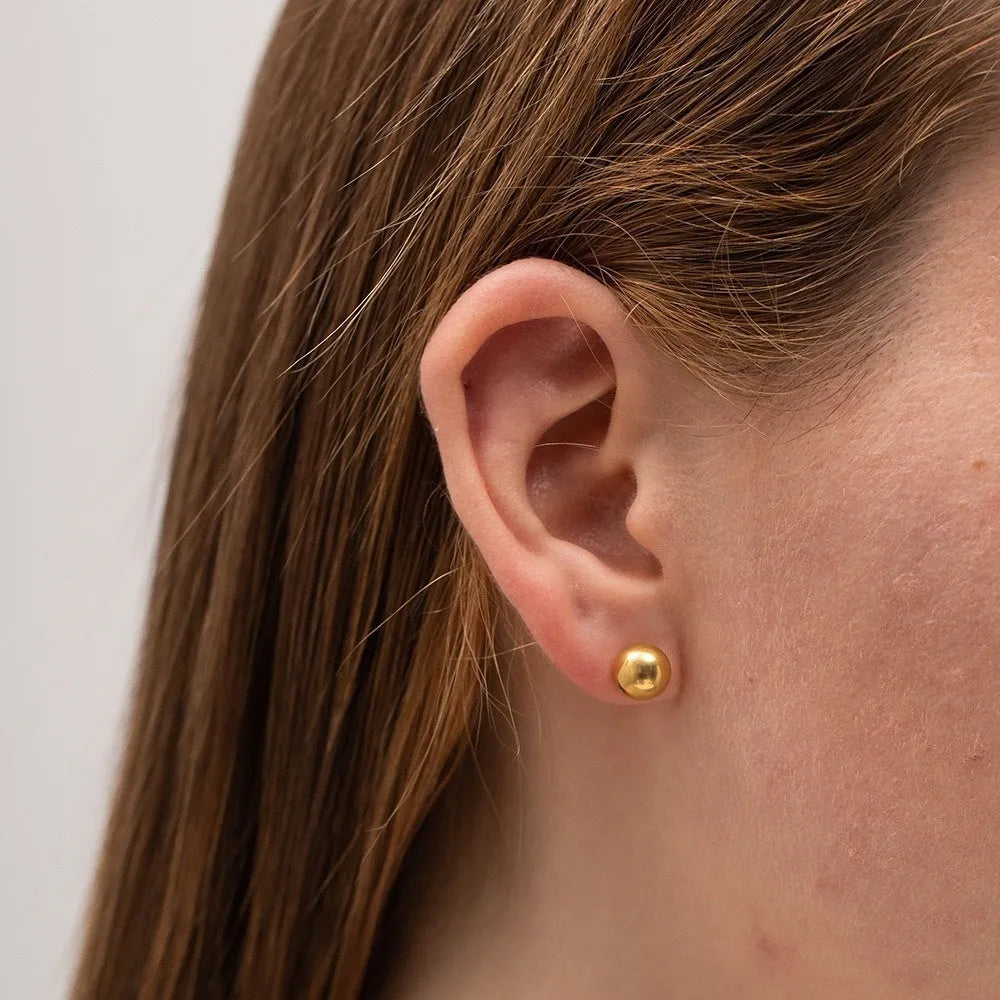 Titanium steel 18K gold electroplated ball stud earrings in round geometric design on white background.