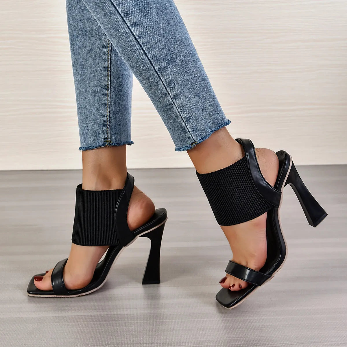 Women's black high heel sandals with elastic straps, showing side profile on a plain background.