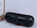 Black portable manual coffee machine showing compact size and manual operation components.