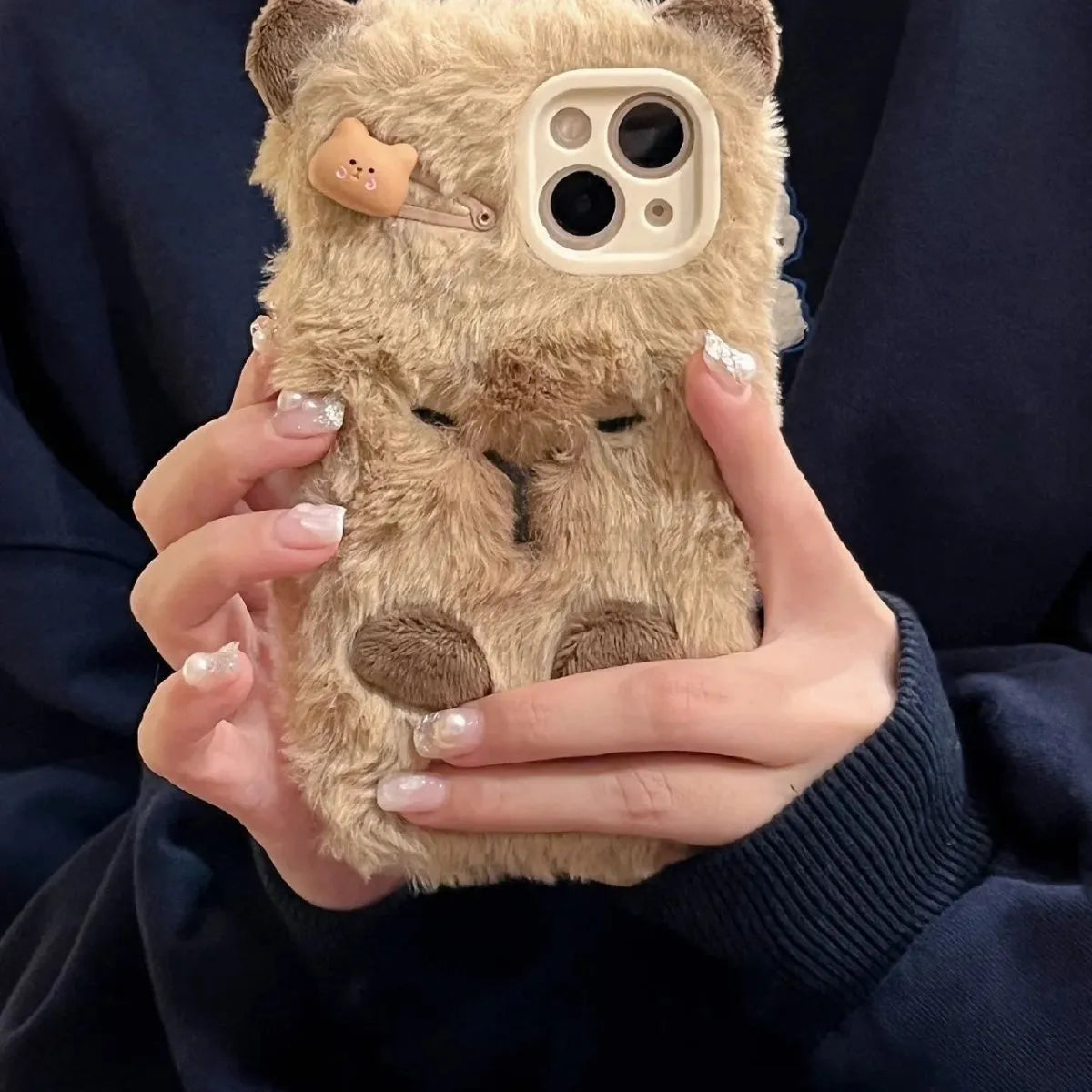 Brown furry plush capabala phone case for iPhone showing cartoon face and flannel texture