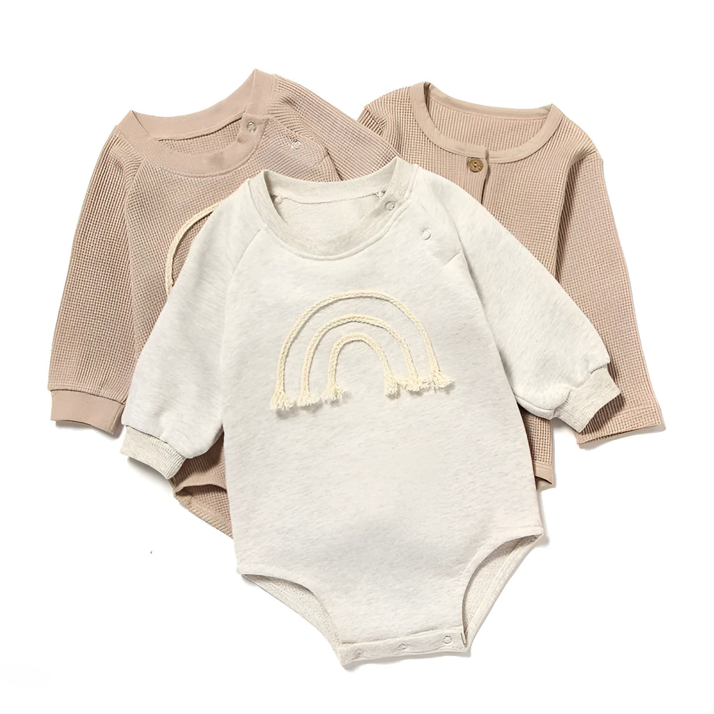 Neutral baby romper in waffle cotton fabric with long sleeves, shown in beige with cotton rope detail.