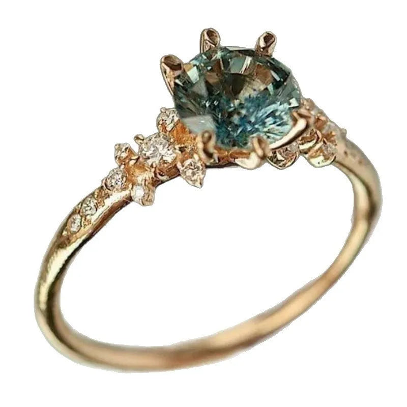 Gold plated geometric ring with a claw setting holding an inlaid zircon stone on a chamfered square pattern band.