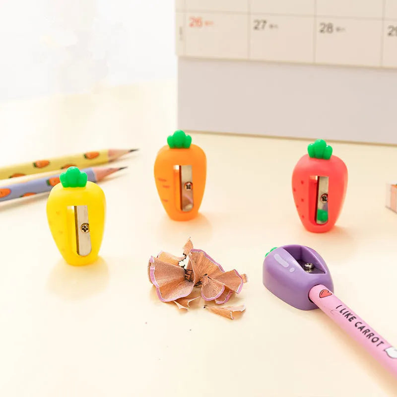 Four fruit and vegetable shaped mini pencil sharpeners in random colours on a light surface
