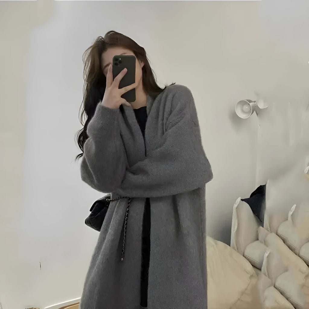 Dark grey loose knitted women's cardigan with a 3D pattern, shown open over a white top.