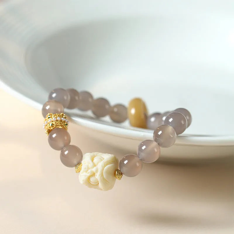Hand-woven bracelet with 10mm round grey agate and mellite beads on a wrist.