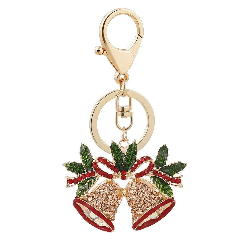 Diamond studded Christmas bell shaped keychain in metal, white diamond colour, on a festive background