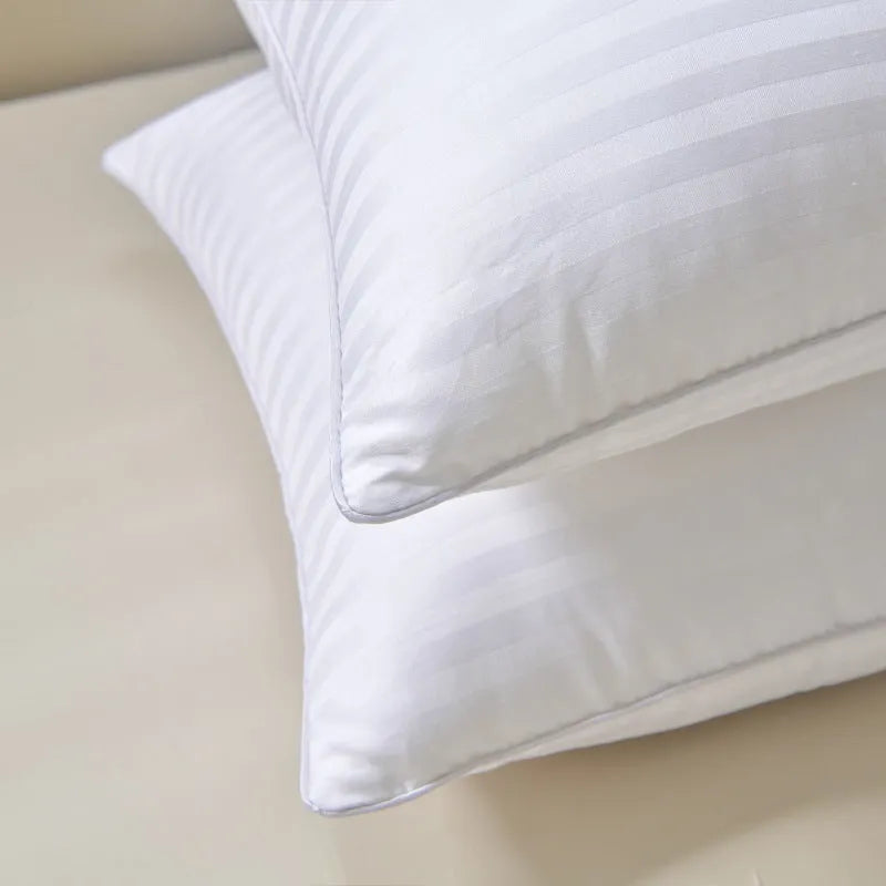 White cotton satin stripe pillow with feather and cotton filling on a bed.