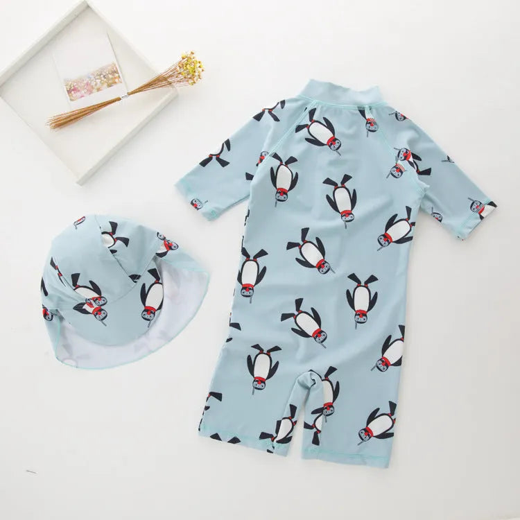 Boy's long sleeve penguin print swimsuit and matching swim cap set on a white background