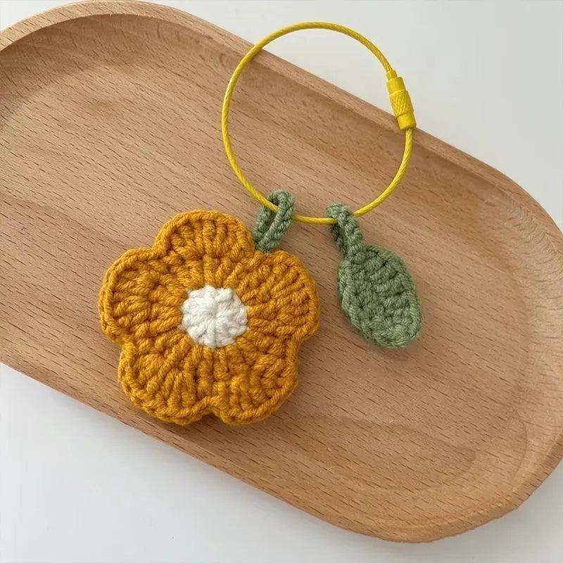 Close-up of a small red hand-crocheted wool flower pendant on a white background.