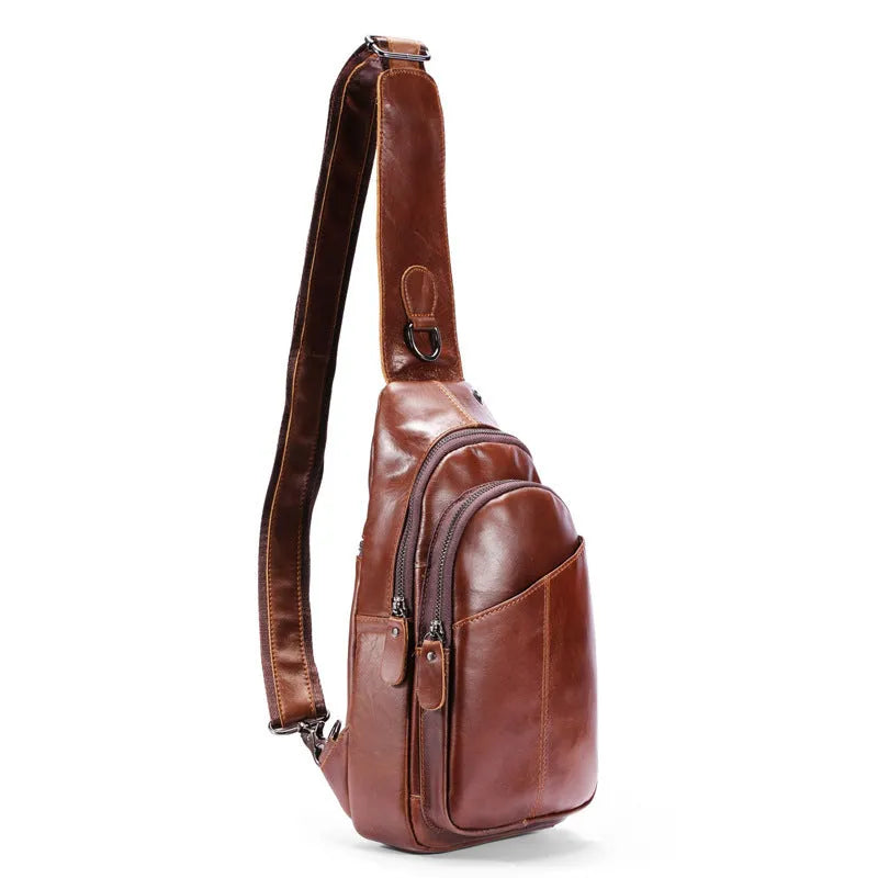 Men's brown cowhide leather crossbody bag with visible stitching and zip closure laid flat on a surface