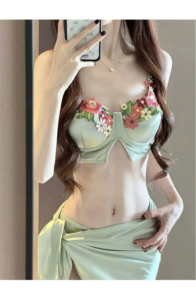 Green women's three-piece bikini set with triangle cup top, briefs, and skirt cover-up