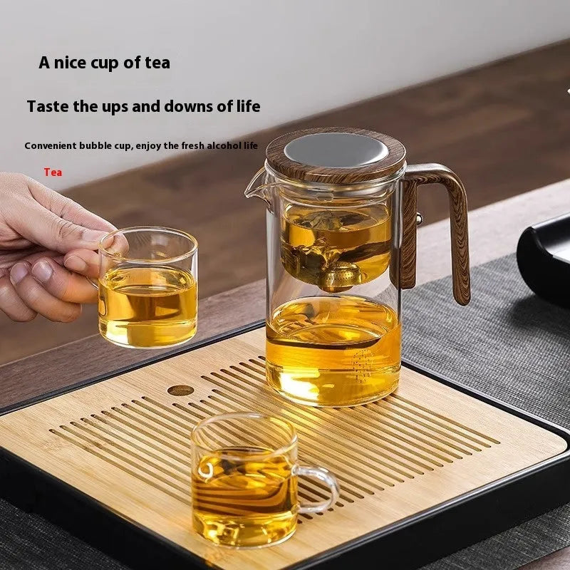 Glass teapot with wooden handle showing magnetic tea separation button and detachable inner infuser.