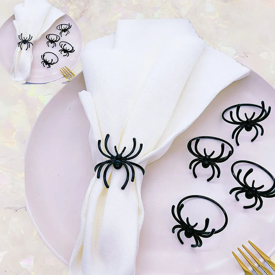 Six black metal spider-shaped napkin rings for Halloween table decoration.